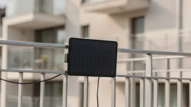Balkon einer Wohnanlage mit befestigtem Solarmodul an der Brüstung und Blick auf die Fassade.