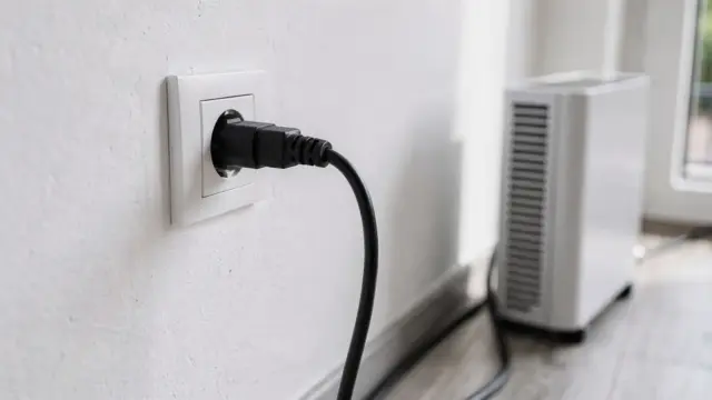 Stecker eines Balkonkraftwerks in einer Haushaltssteckdose neben Kabel und Wechselrichter