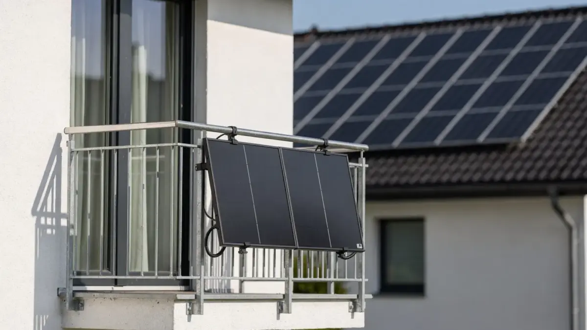 Mehrfamilienhaus mit Balkonkraftwerk am Balkon und Solarmodulen auf einem Hausdach